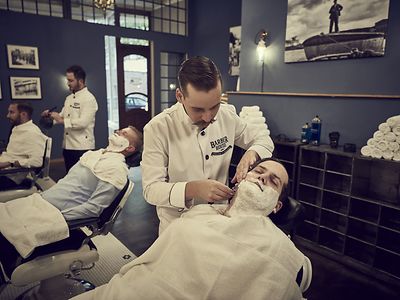  Friseure vom Barber House behandeln Kunden, rasieren und schneiden Haare.