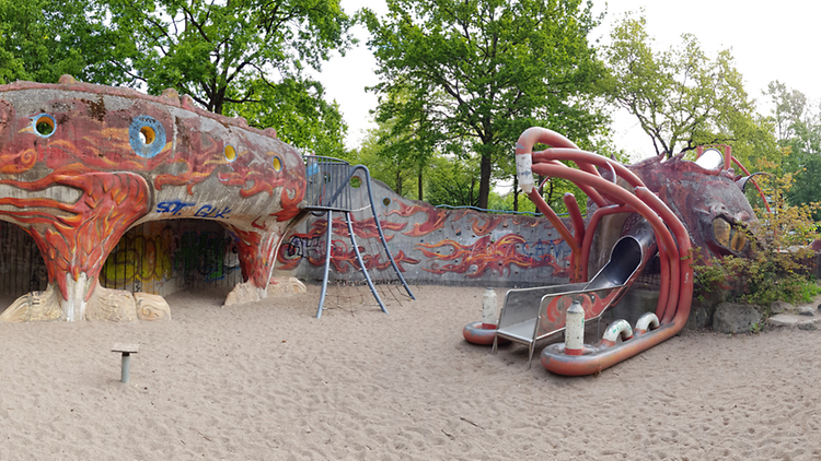  Eine Panorma-Aufnahme eines Spielplatzes mit einer Rutsche in Drachenform.