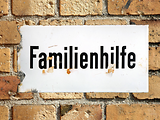  Ein Reklameschild mit der Aufschrift "Familienhilfe" in eine Steinmauer eingerahmt.