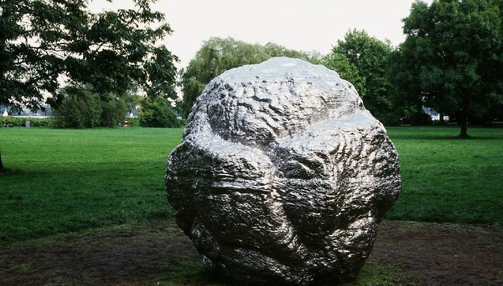 Eine silberne Skulptur im Alsterpark, die wie ein großer Meteorit aussieht