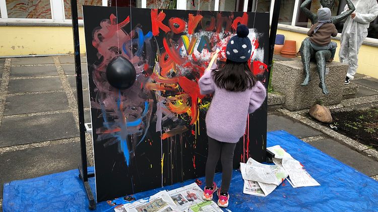  Ein Kind malt an einem Bild auf einer großen Leinwand