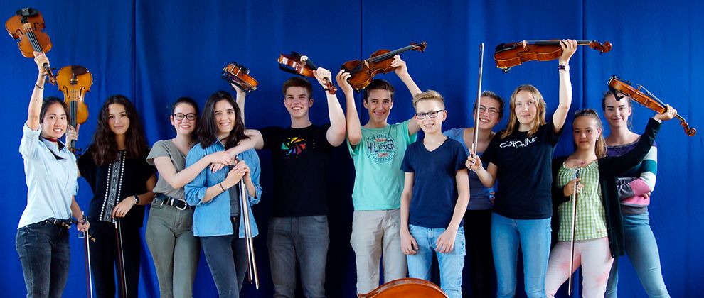  Jugendliche halten ihre Geigen und Bratschen in die Höhe