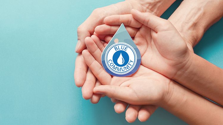  Zwei Paar offene Hände, die ineinander liegen. Sie halten einen Wassertropfen mit dem blauen Logo der Blue Community in den Händen.