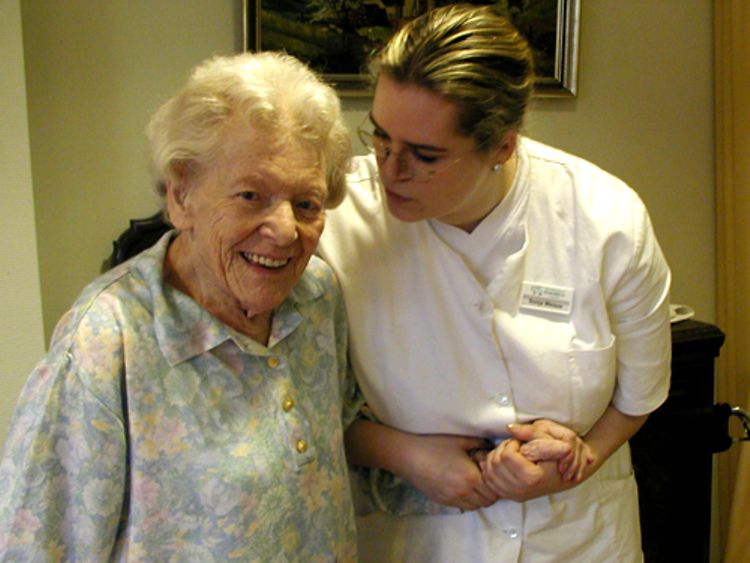  Eine Pflegerin stützt eine alte Dame