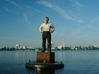  Mann in Hemd und Hose auf einer Boje vor dem Panorama der Außenalster in Hamburg