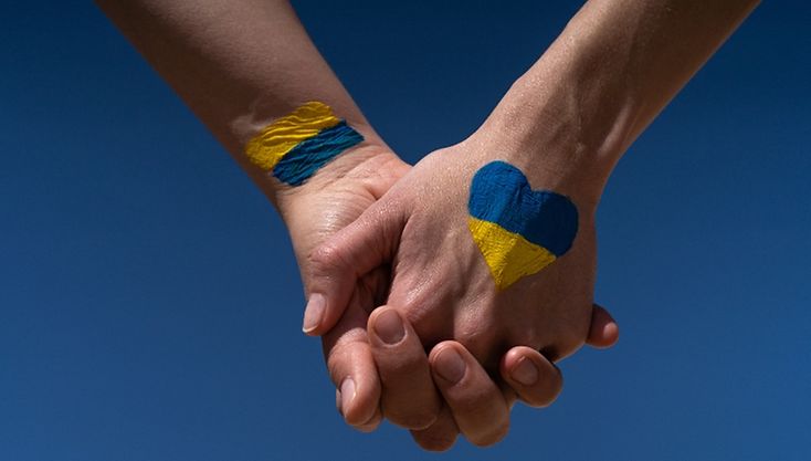 Das Bild zeigt ein Kind, das seine Handflächen zeigt. Die eine ist blau, die andere gelb ind den Farben der Ukraine bemalt.
