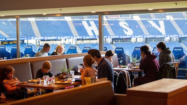 Erwachsene mit Kindern essen im Restaurant im HSV Stadion