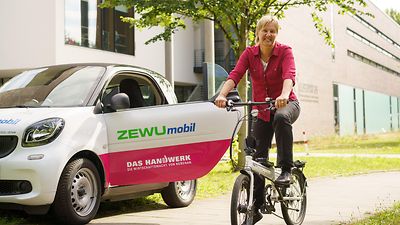  Ein Fahrzeug mit der Aufschrift ZEWUmobil und Frau Lange auf einem Fahrrad