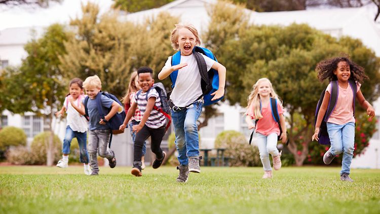  Eine Gruppe fröhlicher Kinder mit Rucksäcken rennt.
