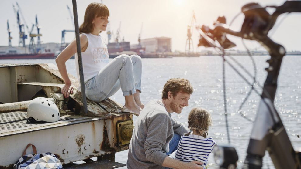 Eine Frau, ein Mann und ein Kind sitzen am Hamburger Hafen.