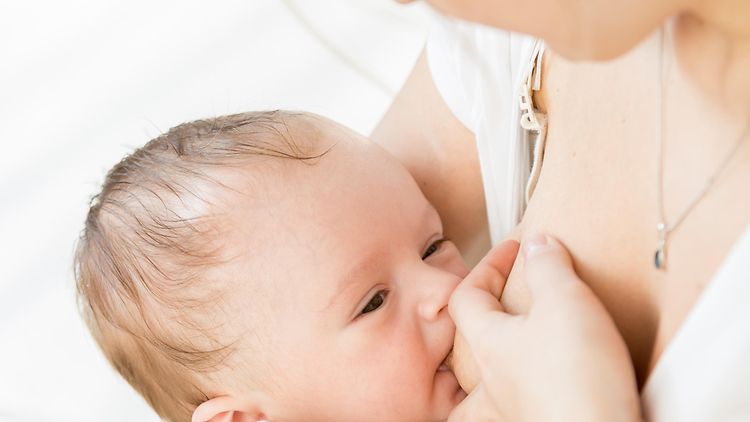  Eine Frau stillt an Baby an ihrer Brust