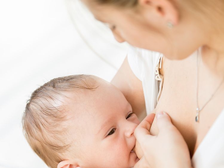  Eine Frau stillt an Baby an ihrer Brust