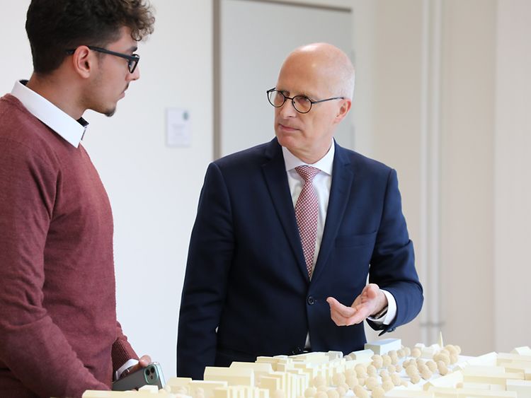  Hamburgs erster Bürgermeister Dr. Peter Tschentscher unterhält sich mit einem Teilnehmer vor einem Stadtmodell.