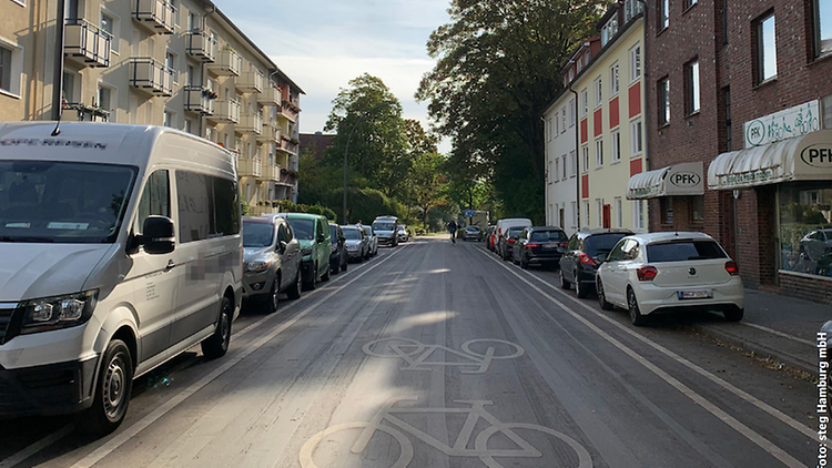  Eine Straße mit rechts und links parkenden Autos und einem Fahrradweg in der Mitte