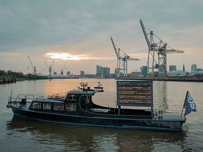  Schute des Kunstprojekts FIDS Open Research Lab im Hamburger Hafen mit elektronischer Anzeigetafel für Vogelflugrouten