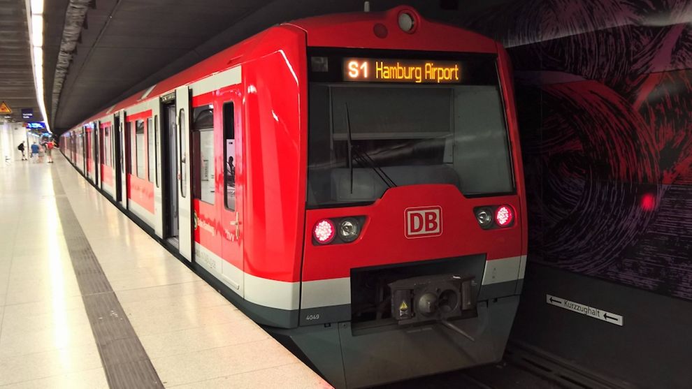Aufnahme einer S-Bahn in Richtung Hamburg-Airport, die an einer Haltestelle steht.