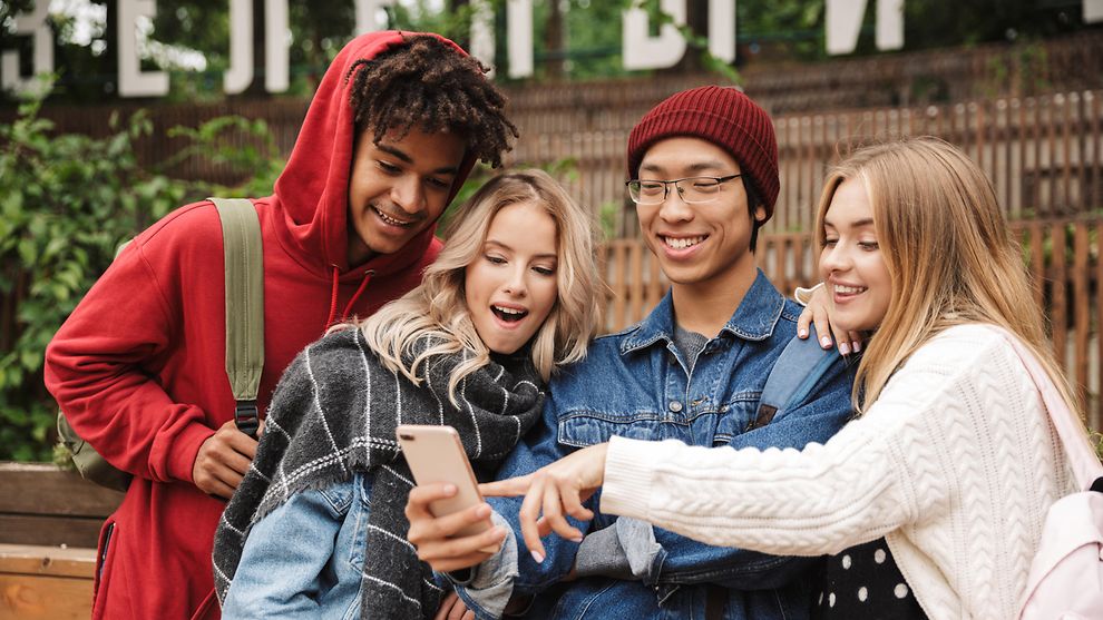 Vier junge Menschen schauen auf ein Handy