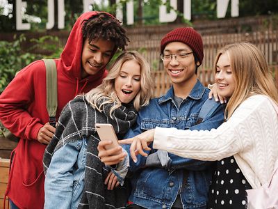  Vier junge Menschen schauen auf ein Handy