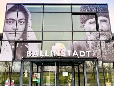  Der Eingang zum Auswanderermuseum BallinStadt, über der Tür ist ein großes Foto von einer Frau und einem Mann angebracht.