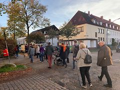  Etwa 20 erwachsene Menschen gehen über eine Straße in Harburg. Im Hintergrund sind einige Wohnhäuser zu sehen.