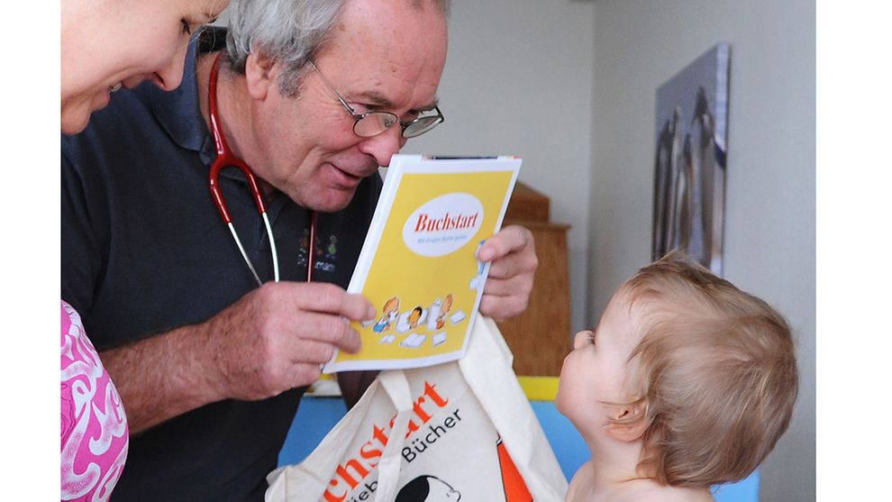Ein Kinderarzt zeigt einem Baby ein Bilderbuch