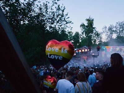  Menge auf einem Festival, im Vordergrund sieht man einen Luftballon mit der Aufschrift "Love is love".