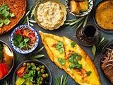  Auf einer Oberfläche stehen Speisen der türkischen Küche, wie Pide, Lahmacun und Gemüse.