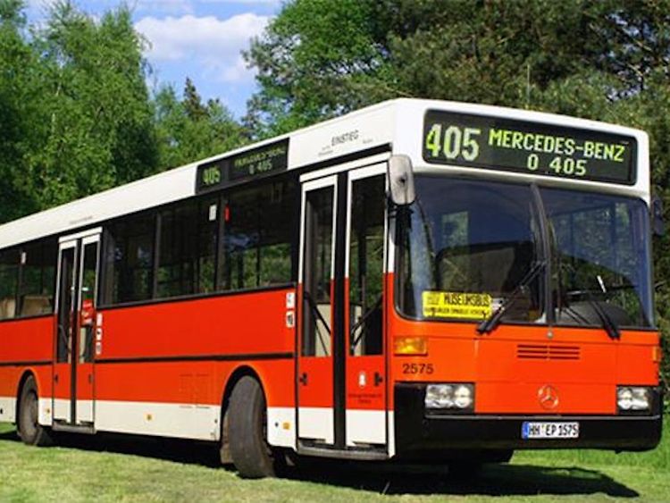  Ein roter Bus, Mercedes Benz O 405, in einer grünen Umgebung.