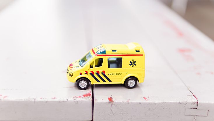 Small toy ambulance car standing in front of a white background