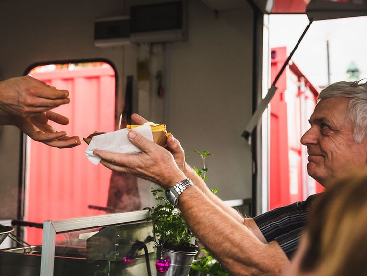  Ein Mann bekommt an einem Food Truck eine Portion Pommes gereicht.
