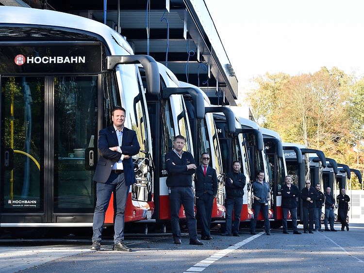  Zehn E-Busse neben denen jeweils ein Busfahrer steht auf dem Busbetriebshof Alsterdorf