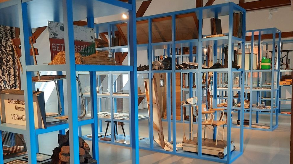Innenraum des Gefängnismuseums Hamburg mit blauen Regalen, in denen Exponate ausgestellt sind.