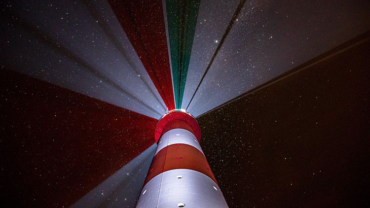  "Leuchtfeuer" - Abgebildet ist ein rot-weißer Leuchtturm mit Licht vor dunklem Himmel.