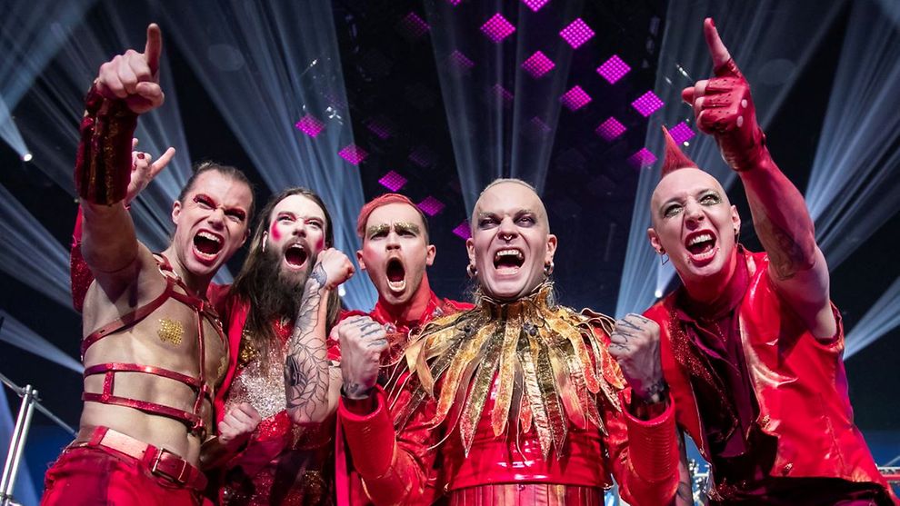 Mitglieder der Band Lord of the Lost tragen rote Latexanzüge und schreien vor Freude.