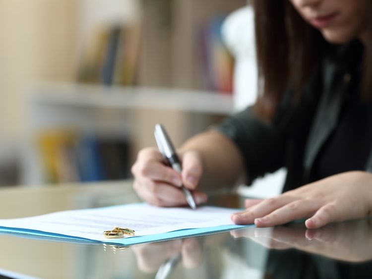 Eine Frau unterschreibt ein Dokument, auf dem Ringe leigen.