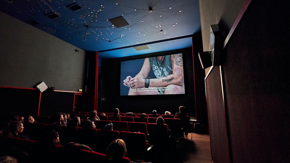  Es ist ein Kinosaal des 3001 Kinos zu sehen, auf der Leinwand läuft ein Film mit Untertiteln.