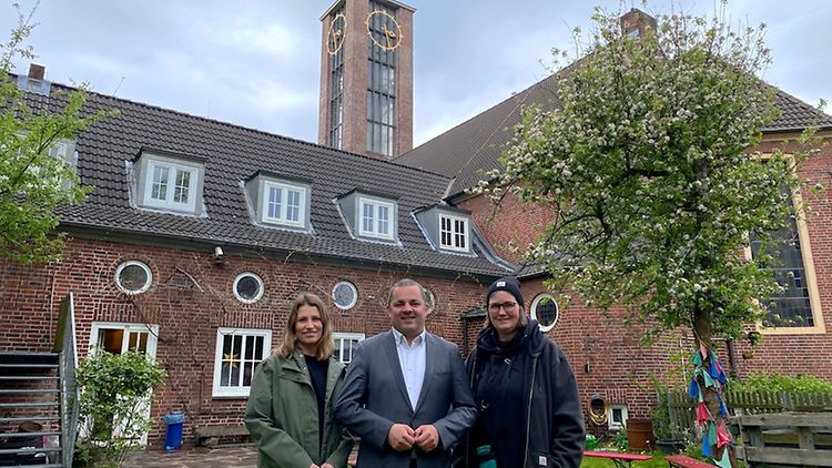 Der Bezirksamtskalender von Hamburg-Mitte steht gemeinsam mit zwei anderen Personen vor der Immanuelkirche.