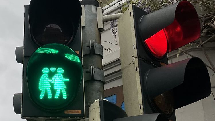  Eine Fußgängerampel zeigt ein grünes Paar Ampelmännchen, das sich an der Hand hält