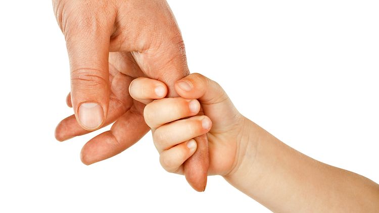 Ein Kind hält den Zeigefinger des Vaters fest.
