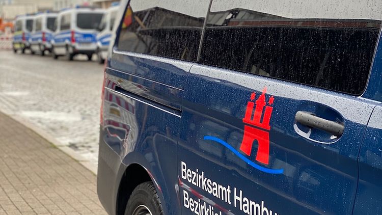  Blaues Fahrzeug mit der Aufschrift Bezirksamt Hamburg-Mitte Bezirklicher Kontrolldienst. Im Hintergrund sieht man mehrere Polizeifahrzeuge.