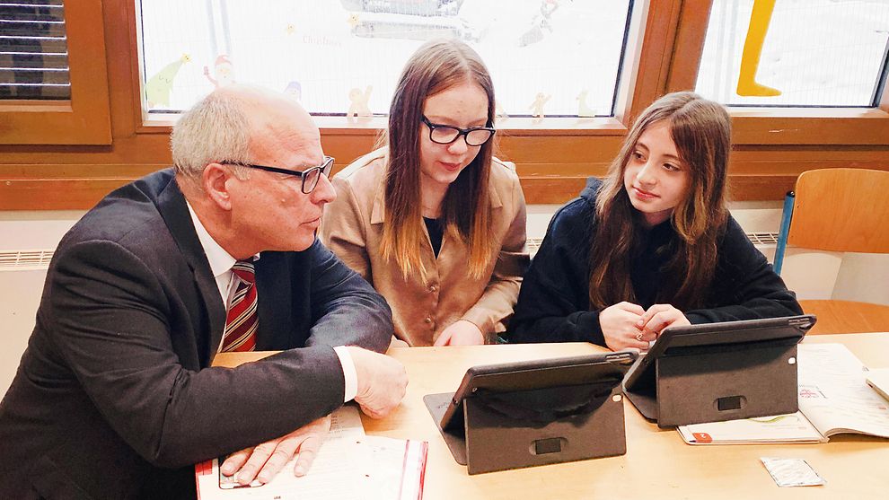 Senator Ties Rabe schaut mit zwei Schülerinnen auf ein Tablet