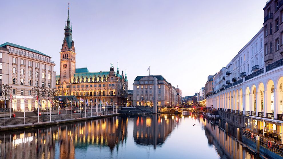 Das Rathaus und ein paar Gebäude rund um ein Gewässer in der Hamburger Innenstadt sind zu sehen. 