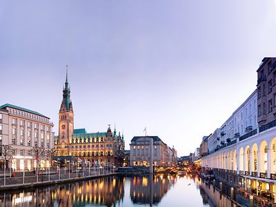  Das Rathaus und ein paar Gebäude rund um ein Gewässer in der Hamburger Innenstadt sind zu sehen. 