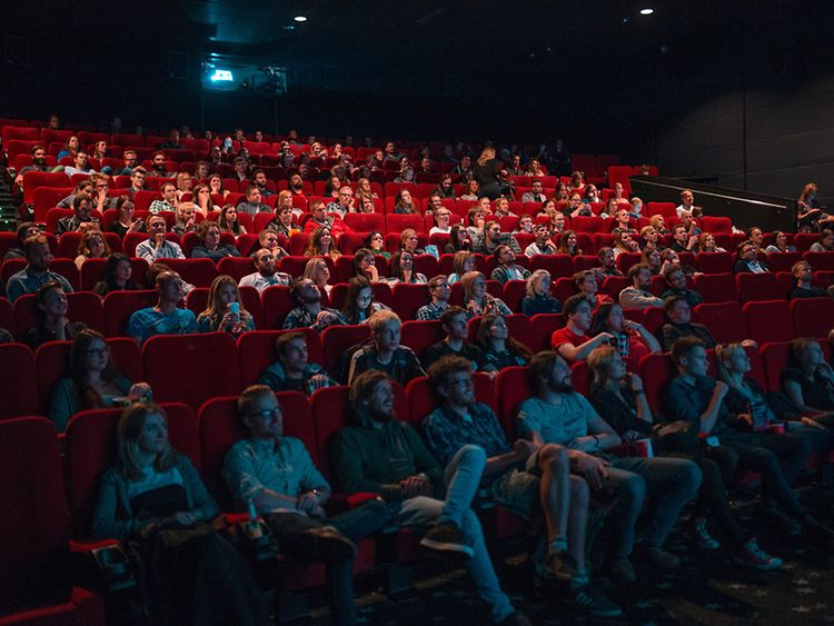  Publikum auf roten Samtsitzen im Kinosaal