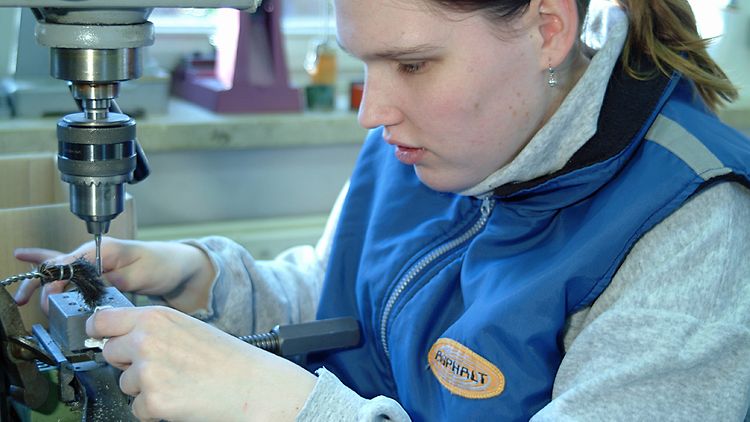  Eine Frau arbeitet an einer Werkbank in einer Werkstatt für behinderte Menschen.