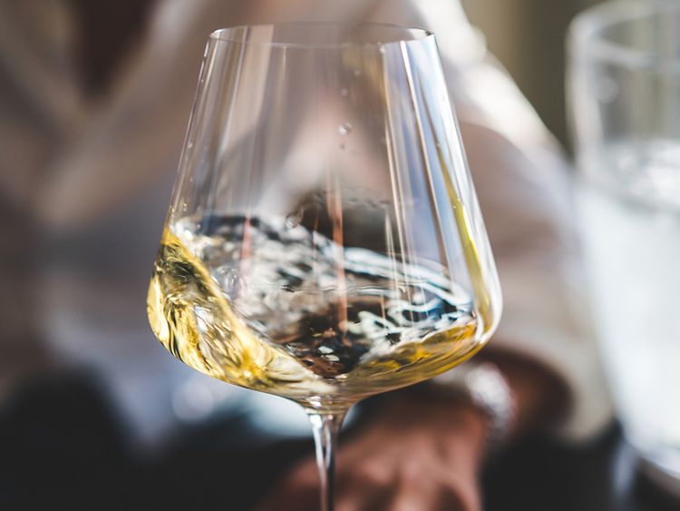  Ein Weinglas mit Weißwein wird geschwenkt. 