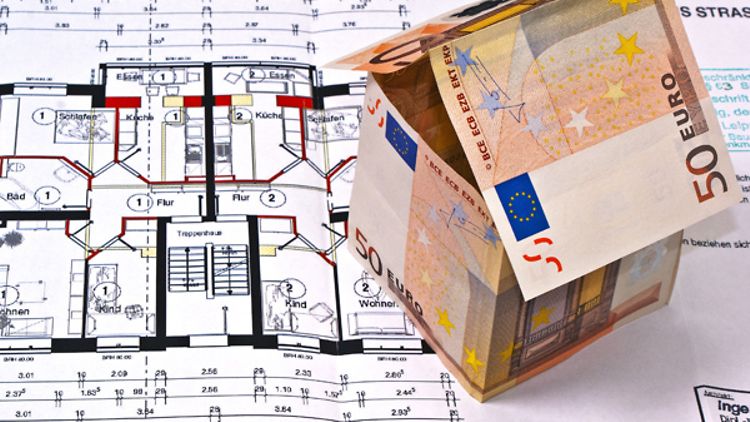  Kleines Hausmodell aus gefalteten Geldscheinen auf Plan mit Grundriss