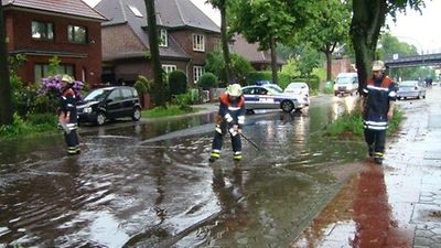  Feuerwehreinsatz an einer Wohnstraße, die nach heftigem Regen überflutetet ist