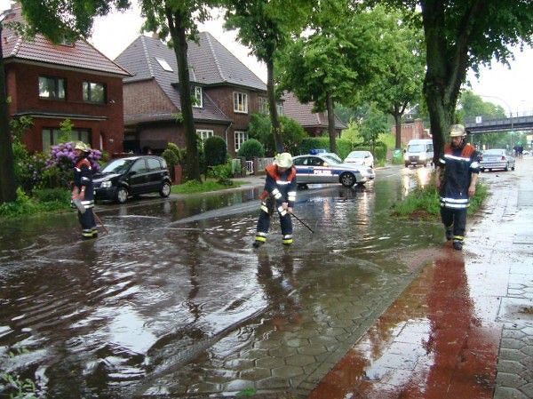 Feuerwehreinsatz an einer Wohnstraße, die nach heftigem Regen überflutetet ist