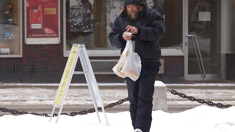  Ein Obdachloser hält eine Plastiktüte in der Hand